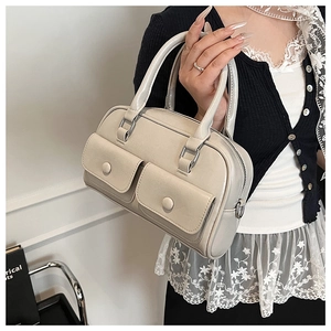 Detail of a beige leather bowling bag featuring front flap pockets and silver hardware