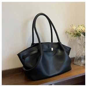 Detail of black tote bag featuring textured faux leather and silver metal buckle accent