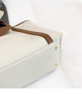 Close-up of litchi grain leather tote bag bottom with protective gold metal feet