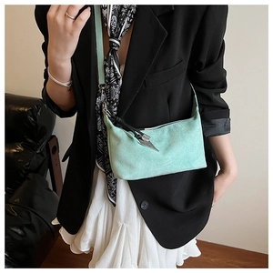 Mint green suede hobo bag with silver spike pendant shown on shoulder of a model