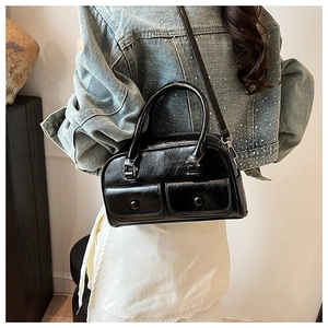 Detail of a black glossy shoulder bag with double buckled pockets and metal hardware