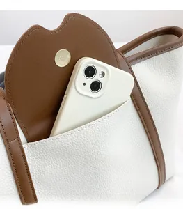 Detail of off-white lychee grain leather tote bag with magnetic front pocket and phone slot
