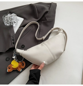 Detail of cream-white lychee grain leather crescent bag with leather elephant charm