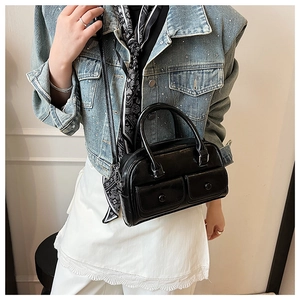 Detail of black glossy Boston bag with two buckle pockets and elegant silk scarf accessory