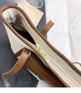 Detail view of gold metal zipper and herringbone lining on ivory leather tote bag