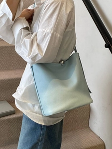 Sac seau en cuir bleu clair avec boucle boule argentée porté par un mannequin en jean
