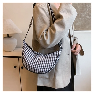 Detail view of black and white checkered crescent bag with adjustable strap worn by model