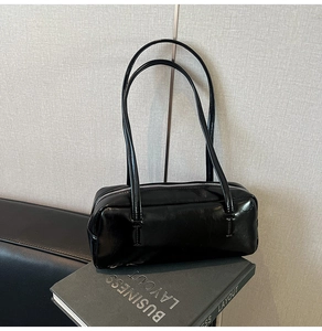 Detail of black glossy shoulder bag with sleek rectangle silhouette and metal zipper