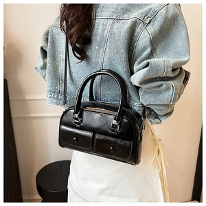 Detail shot of a black glossy Boston bag featuring front pockets and silver hardware detail