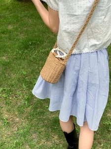 Sac seau en paille tressée avec poignée en perles sur fond d'herbe naturelle
