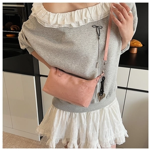 Detail of pink matte crossbody bag showing soft texture and slim shoulder strap
