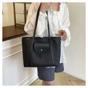 Close-up of black pebble leather tote bag featuring a front pocket with gold snap closure