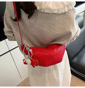 Detail of red leather half-moon bag with lychee texture and cute elephant charm