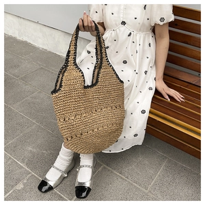 Détail du sac à bandoulière en paille fait main avec bordure noire et tissage ajouré