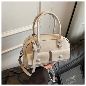Detail of off-white boston bag featuring dual handle straps and decorative front pockets