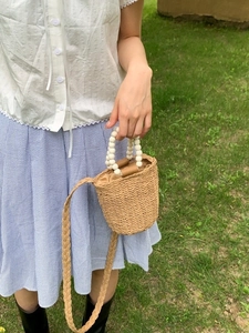 Sac seau en paille beige avec poignée en perles de bois blanches et bandoulière pour l'été