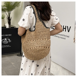 Détail d'un grand sac cabas en paille fait main avec bords noirs et motifs à vagues