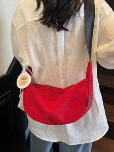 Red crescent nylon crossbody bag with black wide strap and cute capybara charm