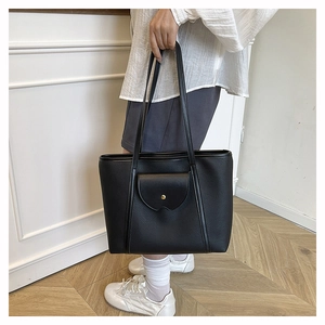 Close-up of black pebble leather tote bag with gold buckle pocket and long shoulder straps