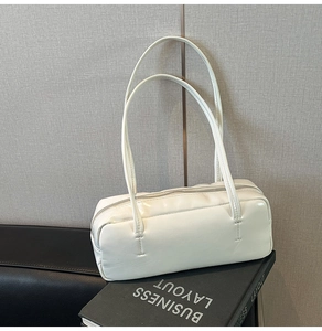 Macro view of cream white leather pillow bag texture and minimalist shoulder strap design