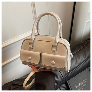 Detail view of a beige leather Boston bag with two front pockets and detachable shoulder strap