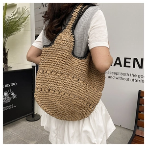 Détail d'un sac hobo en paille tressé à la main avec bordure noire et texture évidée