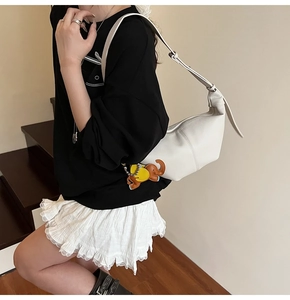 Close-up of white lychee pattern crescent bag with cute elephant charm and shoulder strap