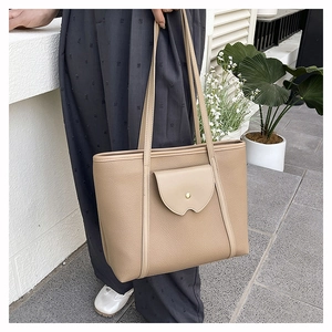 Detail of taupe tote bag featuring lychee texture leather and a wavy pocket design