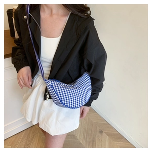 Detail of blue and white checkered crescent shoulder bag with zipper and slim blue strap