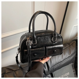 Detail of black glossy patent leather handbag featuring front flap pockets and silver hardware