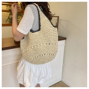 Détail d'un sac cabas en paille tissé à la main avec bordure noire et motifs ajourés