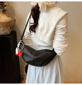 Detail of black pebbled leather crescent bag with silver chain and red elephant charm