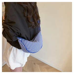 Detail of blue and white gingham crescent crossbody bag with striped shoulder strap