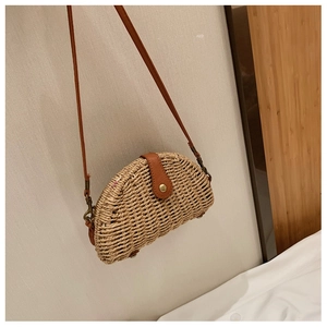 Detail view of woven saddle bag with brown leather strap and gold metal buckle