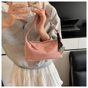 Close-up of pink suede shoulder bag with heart charm in a professional office setting