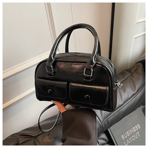 Detail of glossy black Boston bag featuring double front flap pockets and leather handles