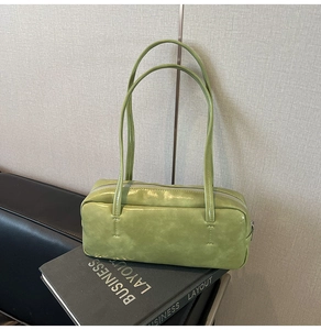 Detail of light green glossy leather shoulder bag on books with thin straps