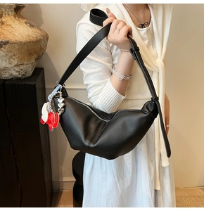 Detail of black crescent moon bag in lychee leather texture with elephant charm accessory