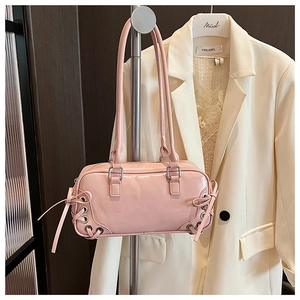 Dettaglio della borsa in pelle verniciata rosa con fiocchi in nastro e occhielli in metallo