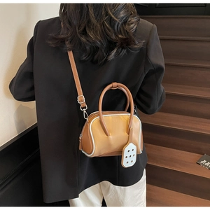 Brown mini bowling bag with light blue piping shown in a stylish crossbody wear detail