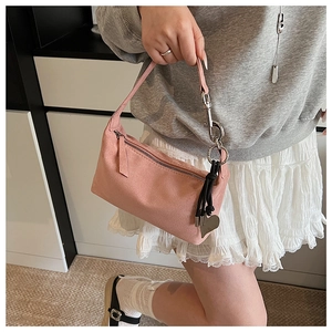 Detail of pink suede shoulder bag with metallic heart pendant and zip closure