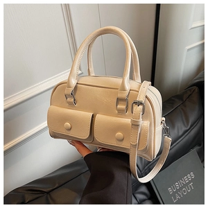Detailed close-up of cream faux leather handbag with multi-pockets and top zipper closure