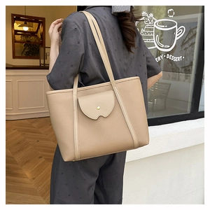 Detailed close-up of beige tote bag with litchi texture and gold buckle on shoulder