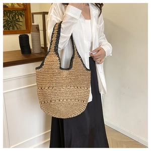 Détail d'un grand sac cabas en paille avec surpiqûres noires et motif tissé ajouré
