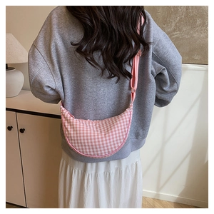 Pink and white checkered crescent crossbody bag with adjustable strap shown on model