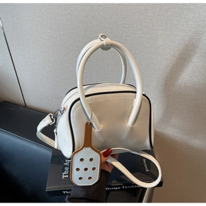 Close-up of white bowling bag with black contrast edges and blue pendant on books