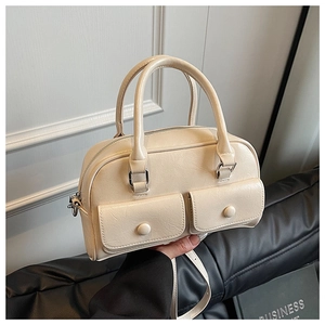 Close-up of beige Boston bag featuring twin front flap pockets and soft leather texture