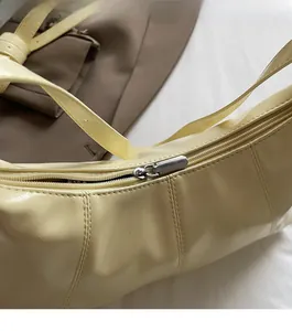 Detail view of the silver metal zipper on the creamy yellow faux leather shoulder bag