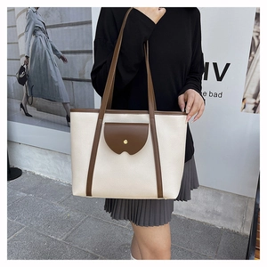 Close-up of the beige pebble leather texture and brown strap details on the tote bag