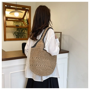 Détail d'un sac cabas en paille tissé à la main avec bordure noire et grand volume